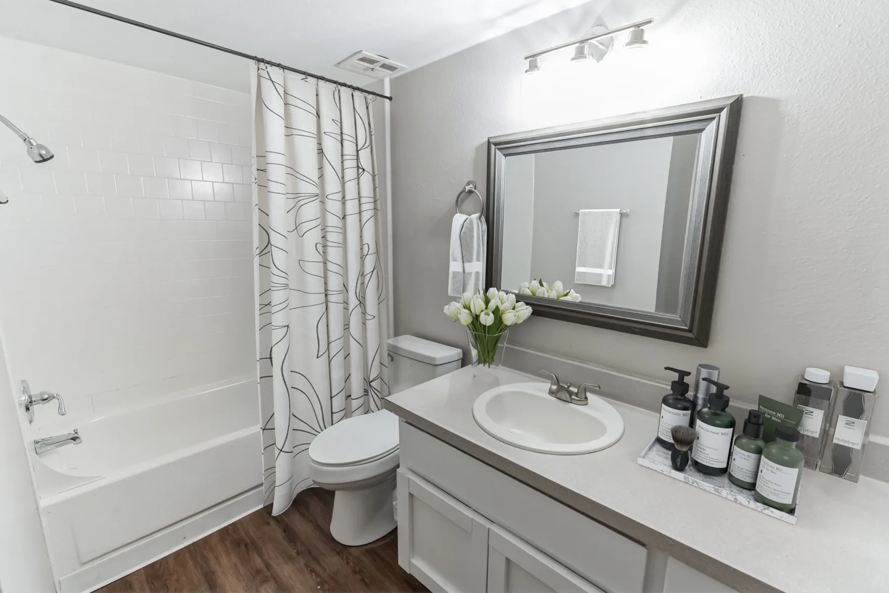 Renovated bathroom with tub shower, vanity and large mirror at Uptown Horizon Apartments