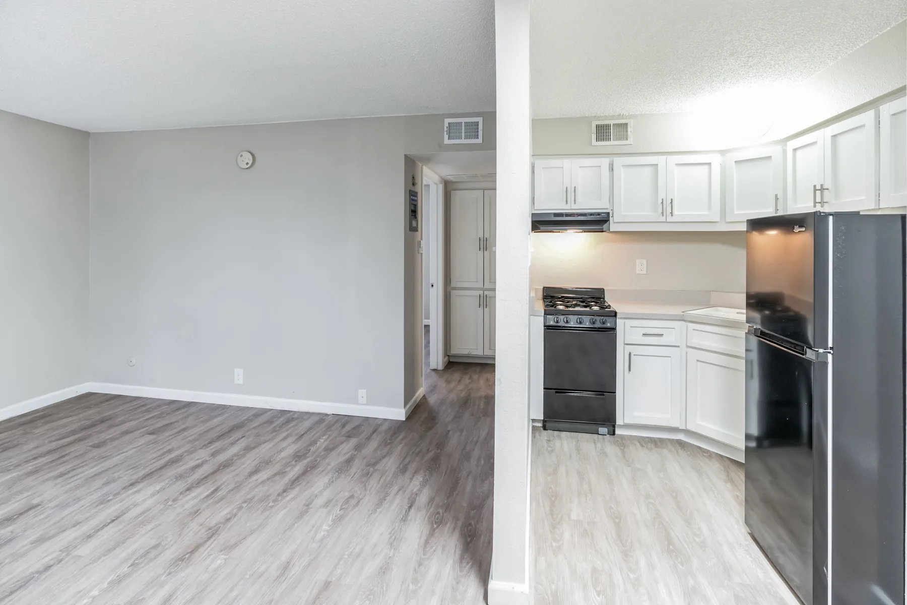Renovated kitchen with white cabinets, black appliances and wood-style flooring at Uptown Horizon Apartments