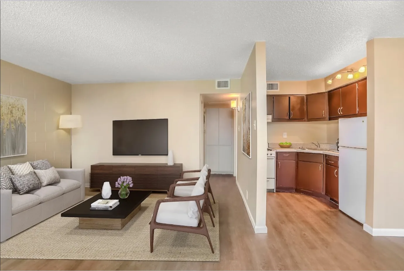 Furnished living room with sofa, TV and open kitchen at Uptown Horizon Apartments